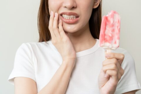 woman wincing and holding popsicle